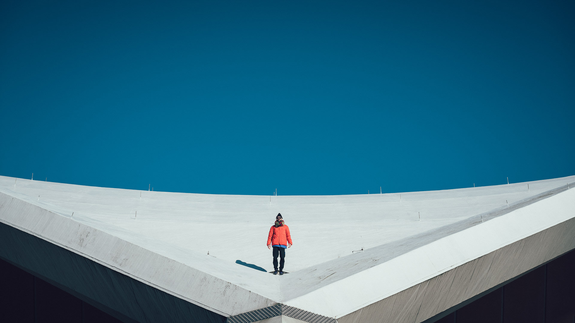 a man standing on a crazy rooftop in berlin , looks like on top of a snowy mountain